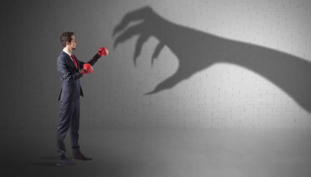 istock Businessman fighting with scary hand shadow 1158782315