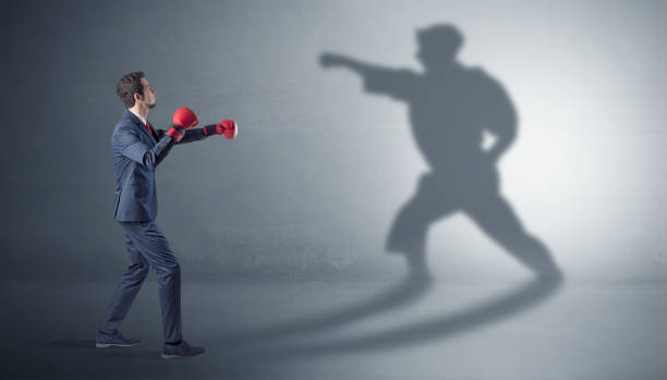 istock Young businessman fighting with his shadow 1158782356