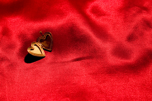 Opened gold locket on red satin background