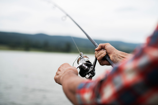 Unrecognizable male hands holding fishing rod and hunting fish.