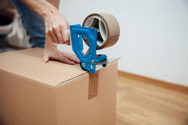 istock Hands of a man using a tape dispenser to seal a shipping box 1158790601