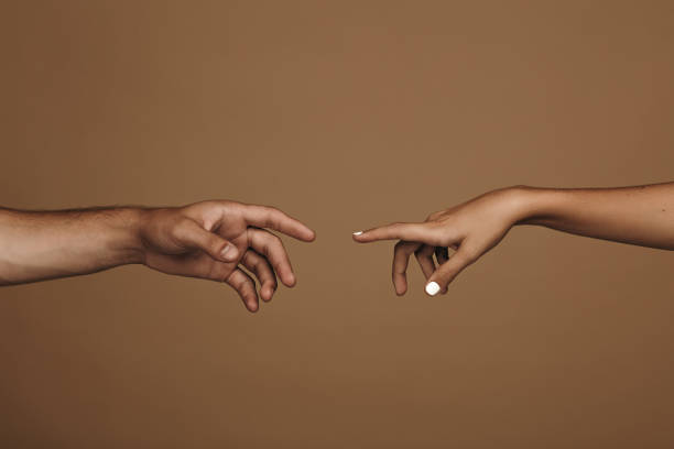 Reaching to one another Close up of man and woman hand about to touch with index finger. Couple in love reaching to one another in front of brown background. approaching stock pictures, royalty-free photos & images