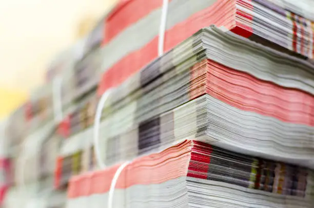 Pile of bundled magazines in offset print plant delivery department, selective focus background