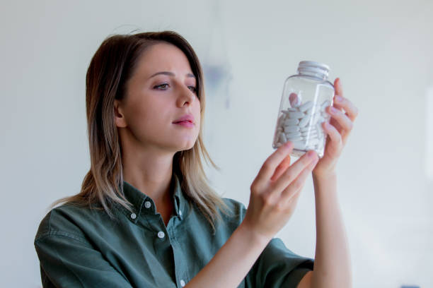 istock woman holding a transparent jar with white pills 1158793709