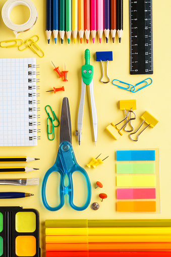 Colorful school stationery and supplies collection on yellow background. Organized desktop space.