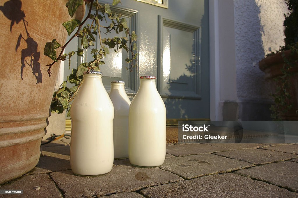 Three jugs of fresh milk sitting at the front doorstep Landscape image of three pints of milk on a doorstep Milk Bottle Stock Photo