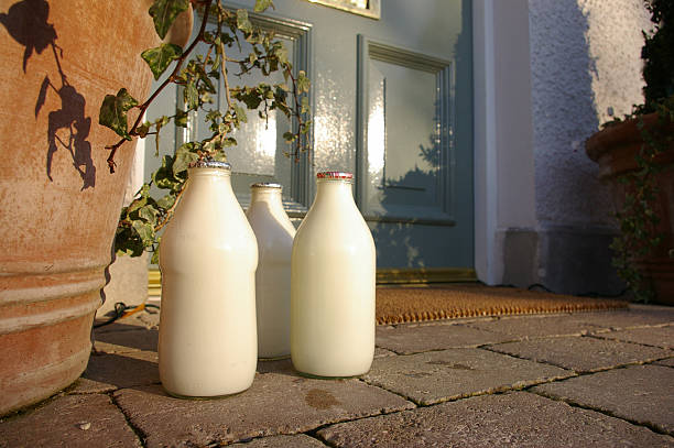 Three jugs of fresh milk sitting at the front doorstep Landscape image of three pints of milk on a doorstep milk bottle stock pictures, royalty-free photos & images