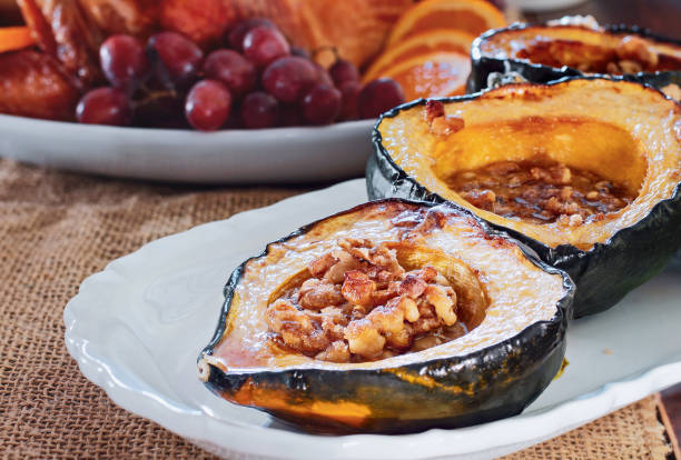 Baked acorn squash with walnuts served for Thanksgiving Day Baked acorn squash with walnuts served for Thanksgiving Day dinner with raost stuffed turkey blurred in background. acorn squash stock pictures, royalty-free photos & images