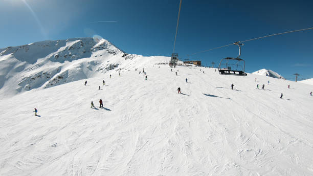 Ski lift with seats going over the mountain with view of people ski and snowboard on slope stock photo