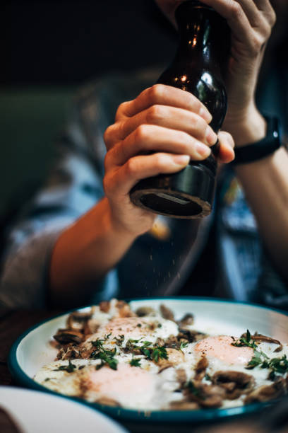 Woman using black pepper grinder