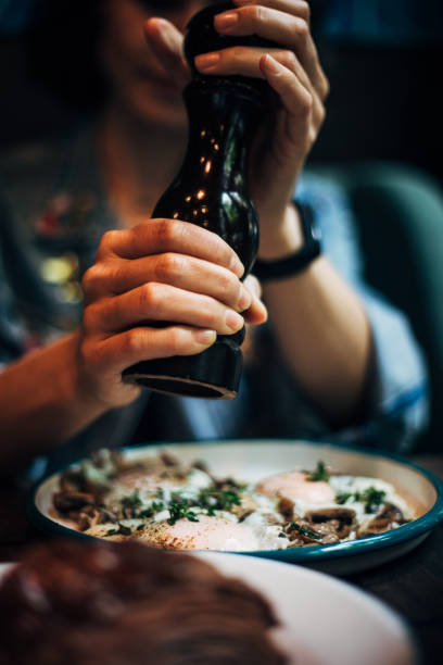 Woman using black pepper grinder