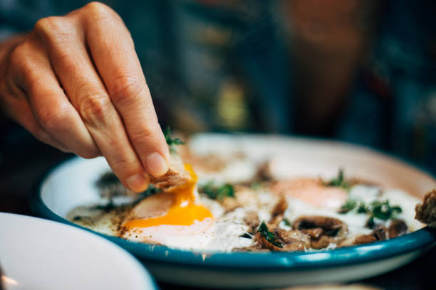 donna che mangia la colazione con uova strapazzate - breakfast eggs fried egg sausage foto e immagini stock