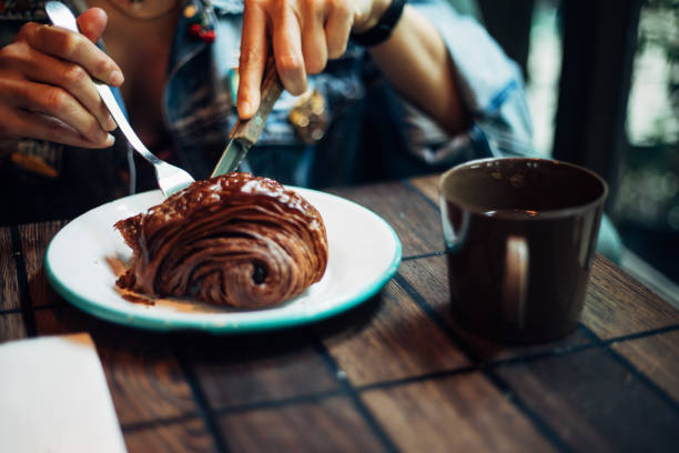 Woman eating chocolate croissant at cafe