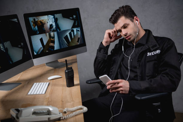 istock tired guard in uniform listening music and using smartphone 1158805552
