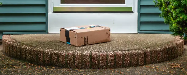 A package is delivered and placed on a wet stoop in the rain in the front of a house exposed to the elements and theft by a delevery service.