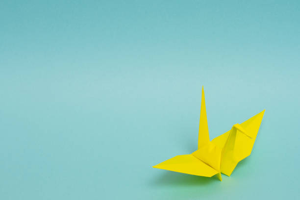 istock yellow origami paper crane on sky blue background 1158806478