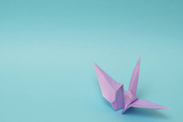 istock light purple origami paper crane on sky blue background 1158806495