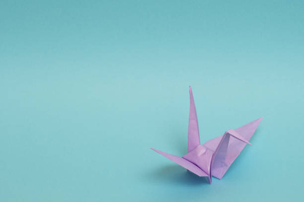istock light purple origami paper crane on sky blue background 1158806498