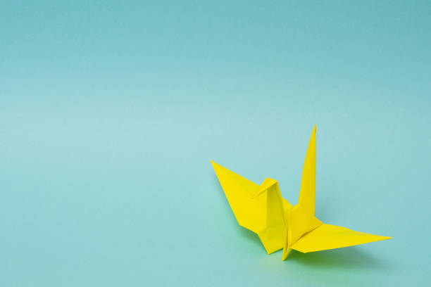 istock yellow origami paper crane on sky blue background 1158806500