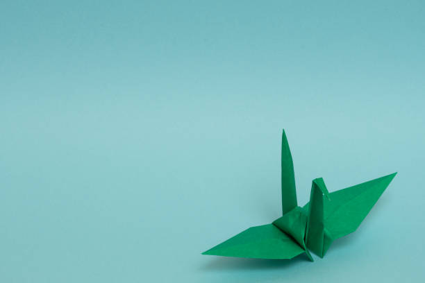 istock green origami paper crane on sky blue background 1158806502
