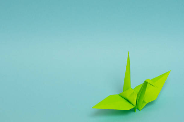 istock light green origami paper crane on sky blue background 1158806503