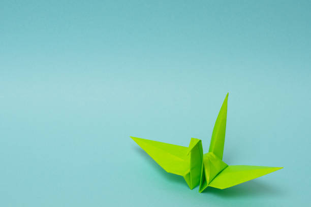 istock light green origami paper crane on sky blue background 1158806505