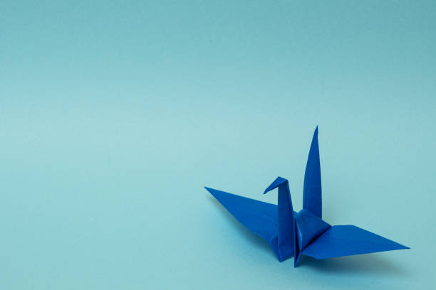 istock blue origami paper crane on sky blue background 1158806536