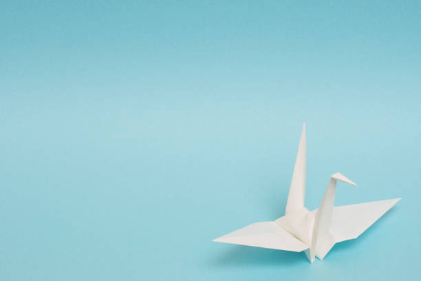 istock white origami paper crane on sky blue background 1158806557