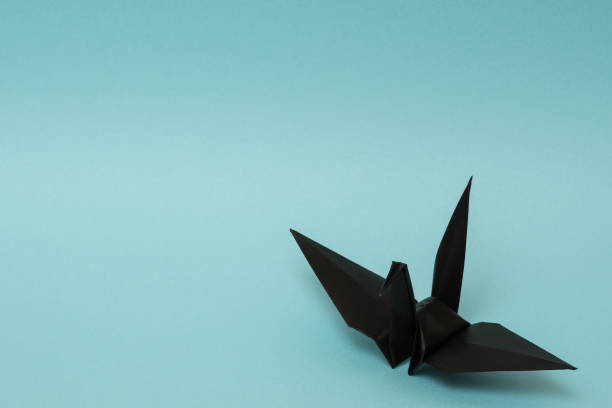 istock black origami paper crane on sky blue background 1158806561