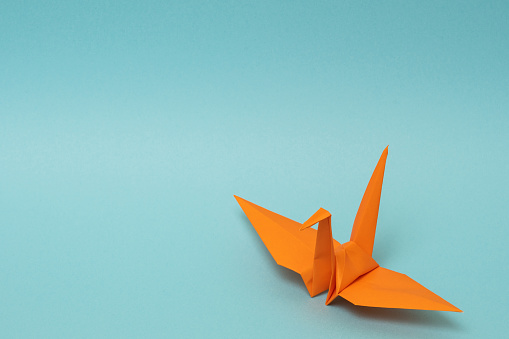 naranja grúa de papel origami sobre fondo azul cielo photo