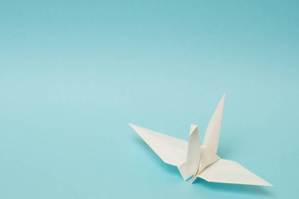 istock white origami paper crane on sky blue background 1158806596
