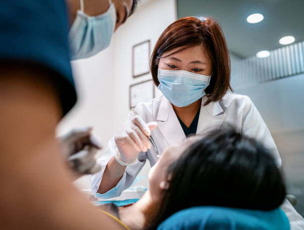 dentiste avec l'assistant masculin traitant le patient féminin - dental assistent photos et images de collection