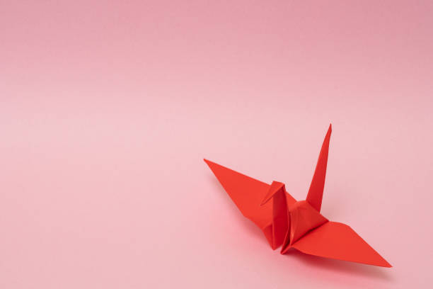 istock red origami paper crane on pink background 1158806661