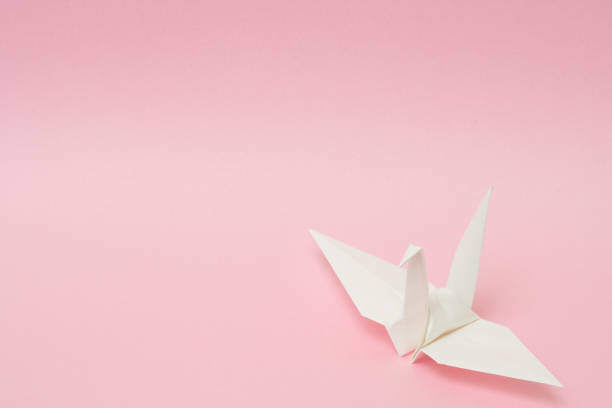 istock white origami paper crane on pink background 1158806665