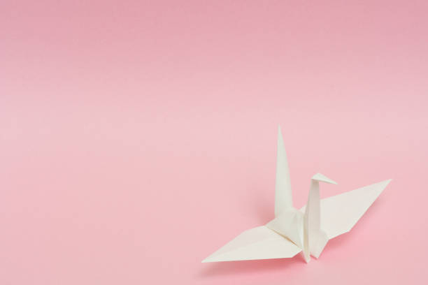 istock white origami paper crane on pink background 1158806733