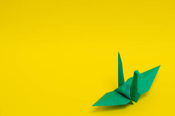 istock green origami paper crane on yellow background 1158807366