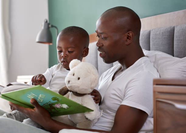 papà che legge le storie della buonanotte al figlio - bedtime stories foto e immagini stock