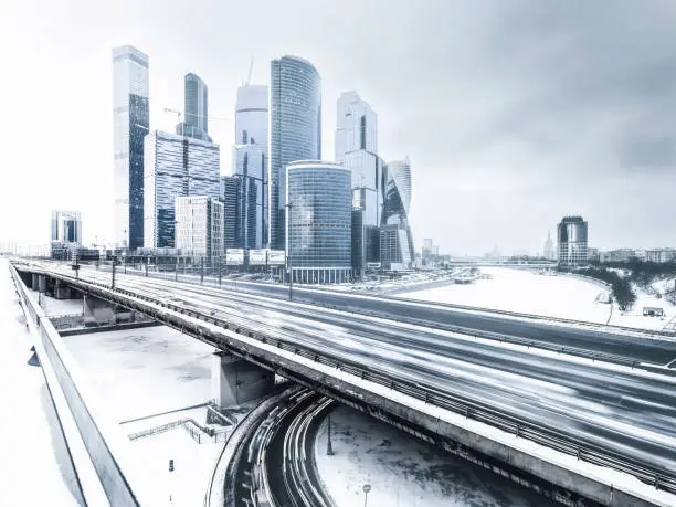 Wide angle view of snowy cityscape of modern finance district of Moscow International Business Center and rush hour on elevated highway in winter