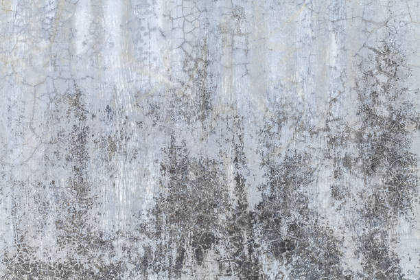 istock Old gray wall covered with uneven plaster. Texture of vintage shabby silver stone surface, closeup. 1158813219