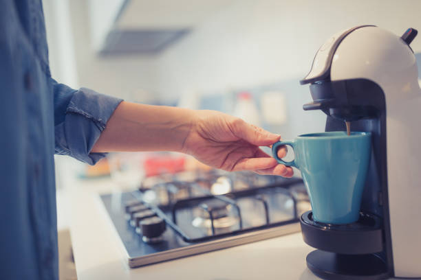 Young woman is making morning coffee in her kitchen.