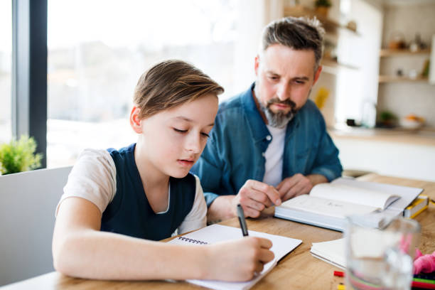 istock Mature father with small son sitting at table indoors, making homework. 1158815006