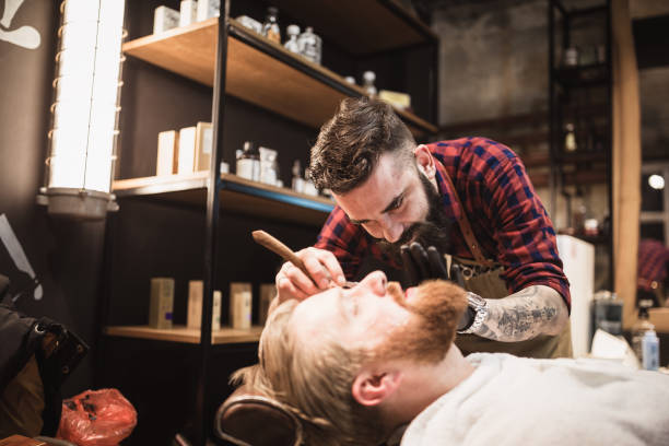 Ginger, bearded guy at the barber shop. Barber cutting a beard