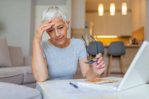 istock Mature woman is sitting upset with documents and thinking at the home 1158815231