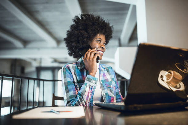 istock African-American Ethnicity, working at laptop in cafe, using mobile phone. 1158815436