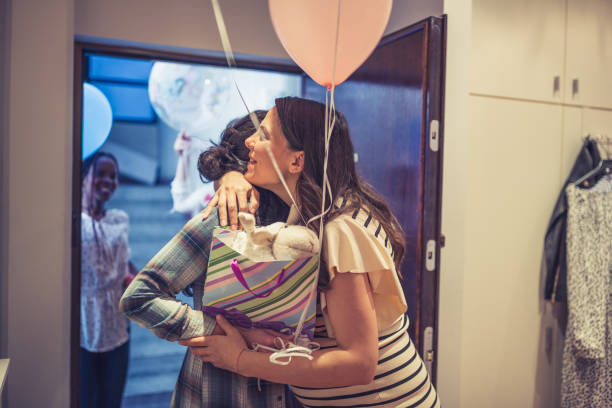Coming in to baby shower party Pregnant woman welcoming her girlfriends on the doorway cute pregnant woman with gift stock pictures, royalty-free photos & images