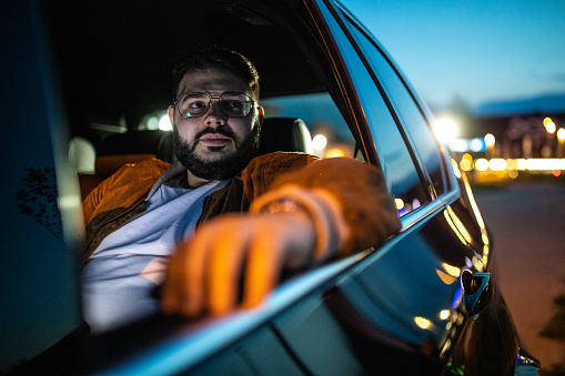 Portrait of an elegant man driving a car, luxury nightlife,.man in a car at night.
