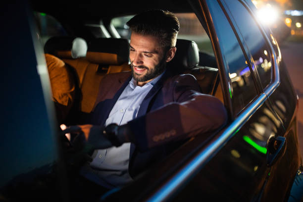 istock Businessman driving in a car at night and using smart phone 1158819594