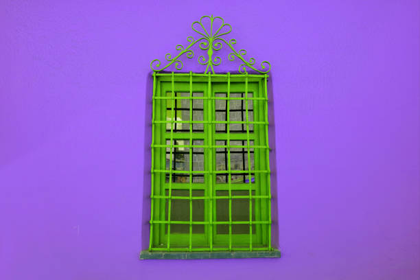 istock Green wrought iron window on purple concrete wall 1158819733