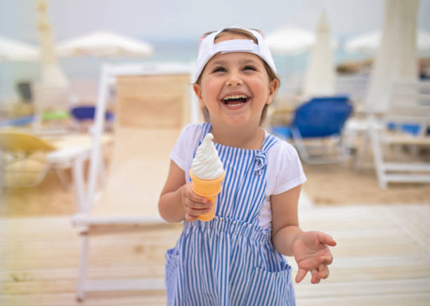 istock Cheerful candid child having fun on the beach and eating ice cream 1158823863