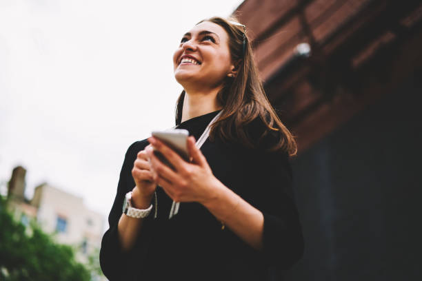istock Beautiful prosperous female blogger dressed in trendy outfit enjoying resting outdoors while chatting with followers in social network.Young smiling woman shopping online during walking at street 1158824272